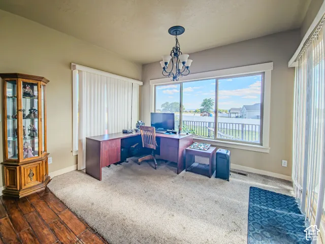 Room featuring a chandelier, large windows with vertical blinds, and a combination of wood-finish flooring and carpet