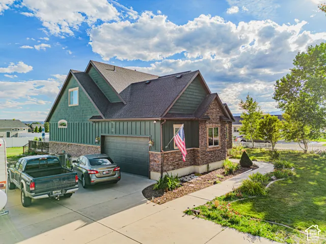 Two-story exterior with a stone and board-and-batten facade, attached garage, and a concrete driveway
