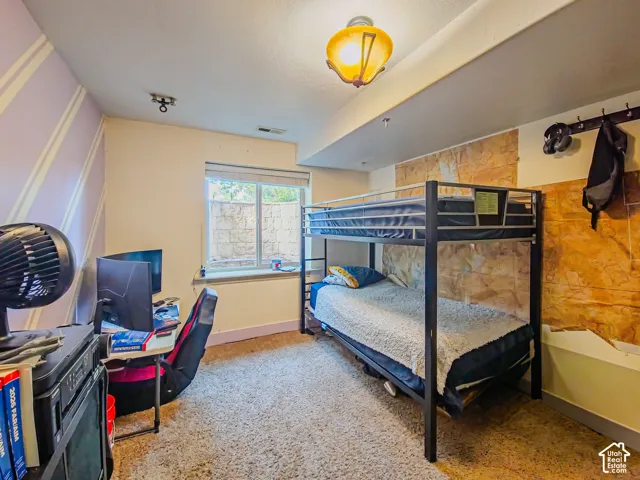 Carpeted room featuring a window, built-in wall texture, and overhead lighting