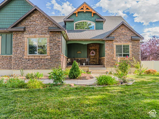 Stone veneer exterior with shake siding accents, gabled rooflines, covered front porch, and mature landscaping