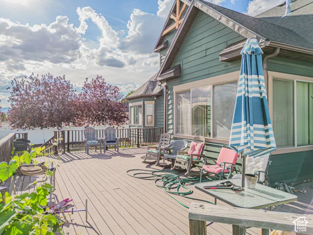 Expansive outdoor deck with wood-finish decking, dark wood railings, and an adjacent siding exterior