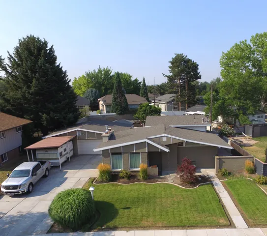 Mid-century modern exterior featuring a two-car garage, established front landscaping, an extended driveway, and a covered side patio