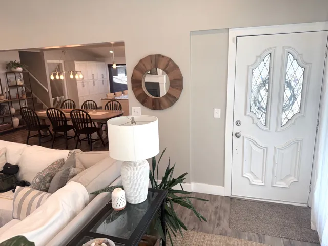 White entry door with decorative glass inserts, wood-finish flooring, and neutral wall paint