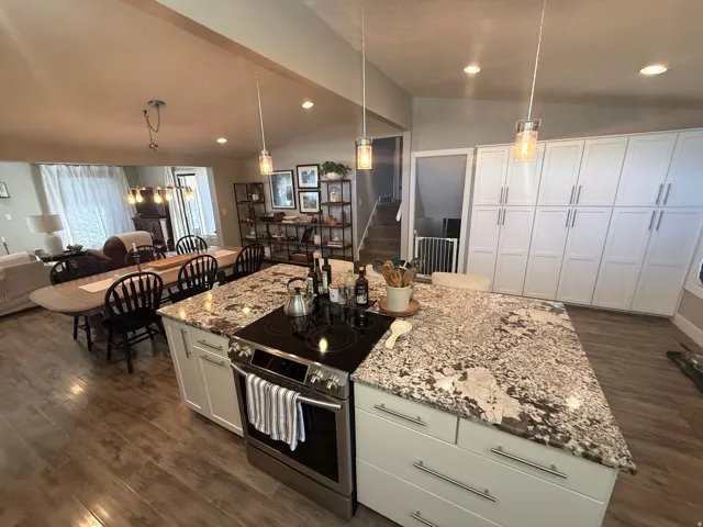 Kitchen island with stone-finish countertop, stainless steel range, and white cabinetry