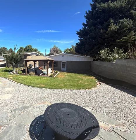 Landscaped backyard featuring a covered patio, gazebo, and grass area