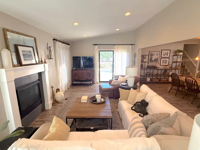 Vaulted ceilings, recessed lighting, wood-finish flooring, a fireplace with a mantel, and sliding glass doors
