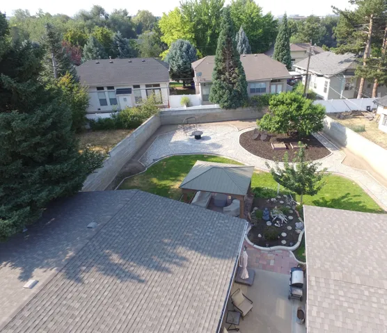 Expansive backyard featuring a stone retaining wall, gravel pathways, a dedicated patio area, and mature landscaping