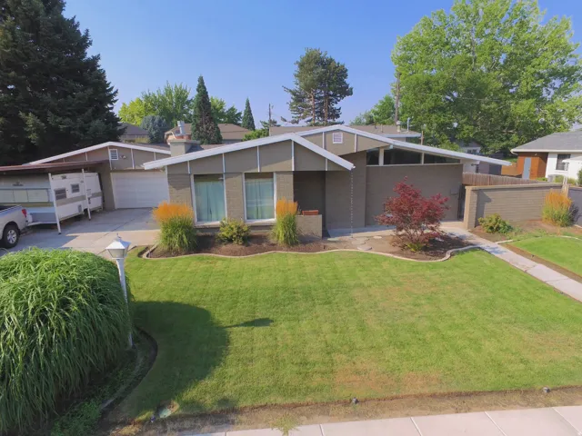 Mid-century modern residence featuring a brick facade, integrated garage, and a covered carport