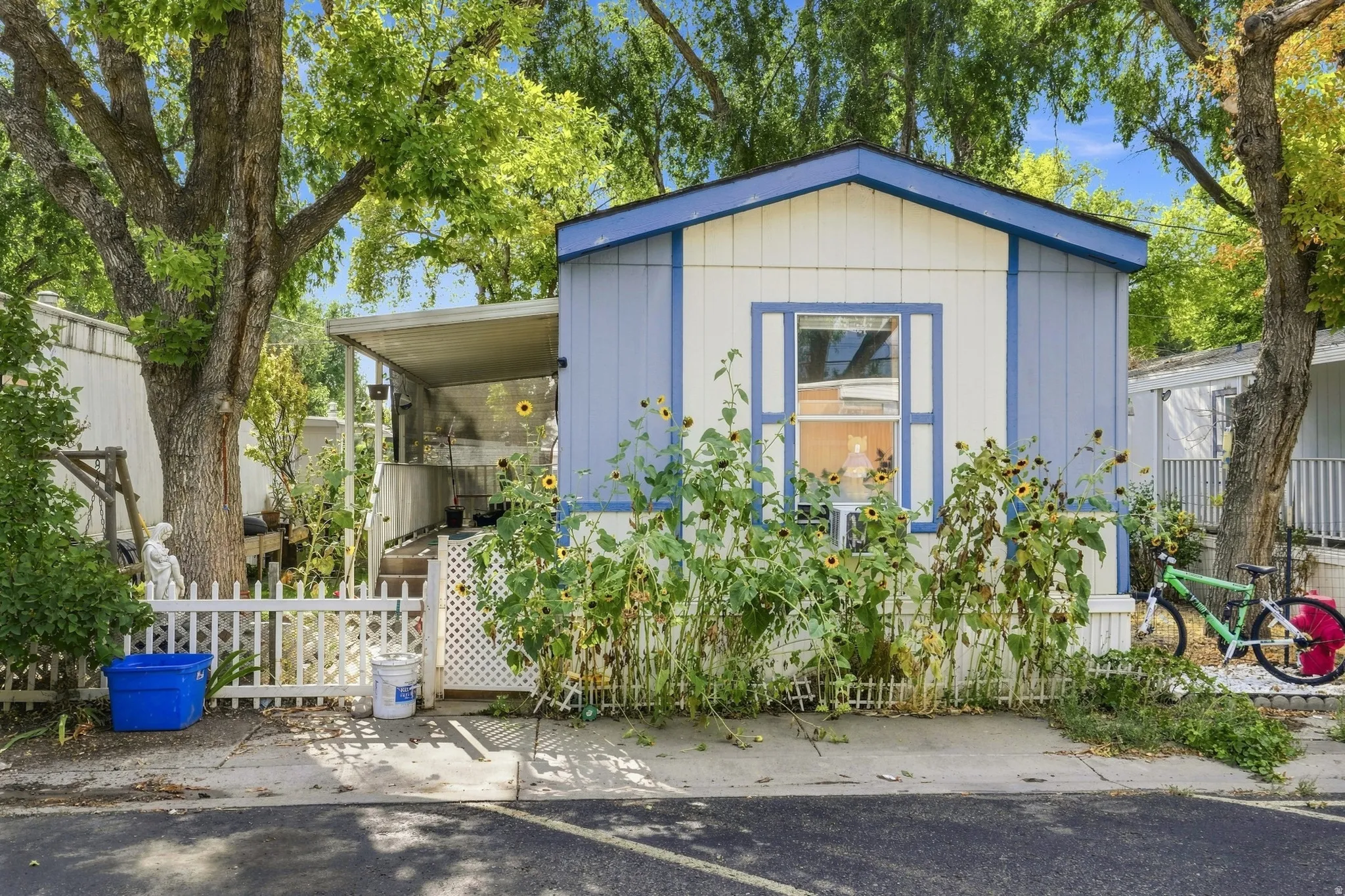 Pale blue and white exterior with contrasting trim, gabled roofline, and a prominent front window with decorative shutters