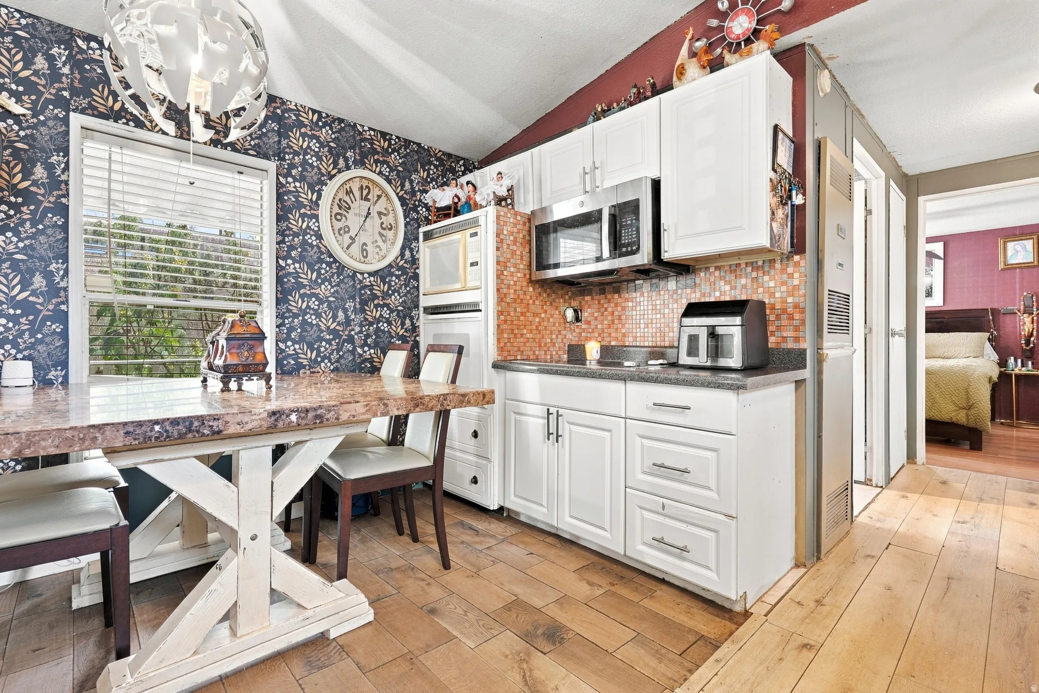 Compact kitchen featuring white cabinetry and stainless steel appliances