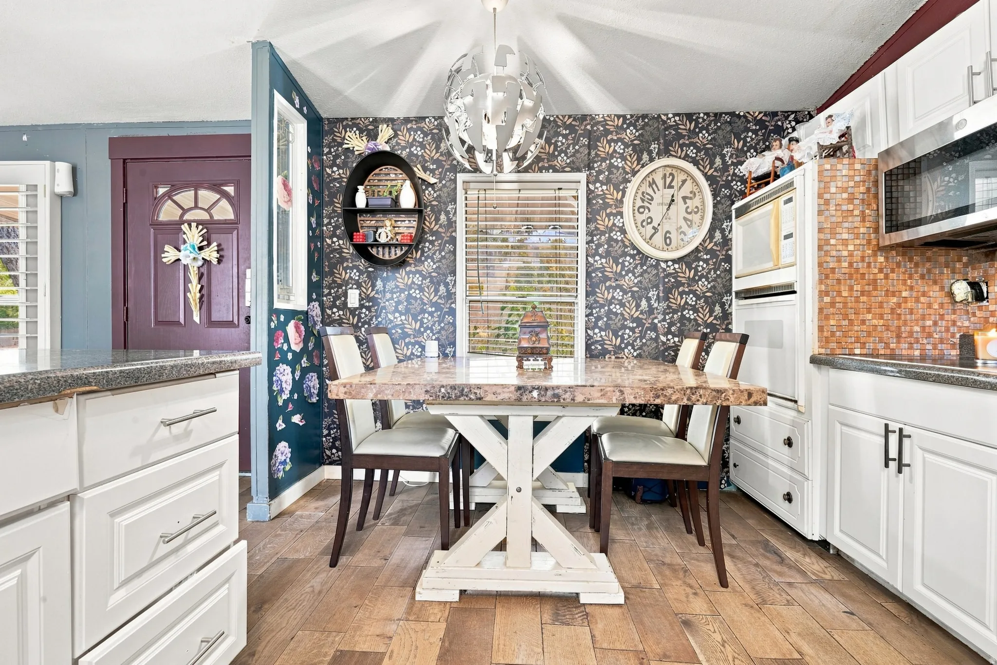 White cabinetry with modern hardware, wood-finish flooring, a mosaic tile backsplash, and a built-in oven and microwave