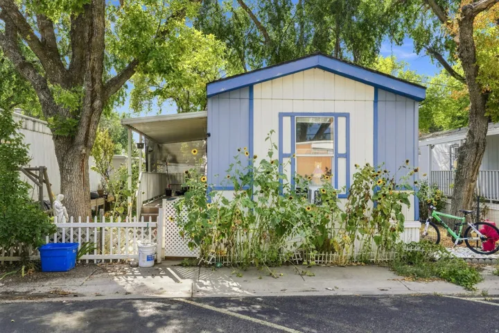 Pale blue and white exterior with contrasting trim, gabled roofline, and a prominent front window with decorative shutters