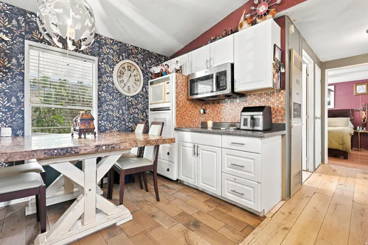 Compact kitchen featuring white cabinetry and stainless steel appliances