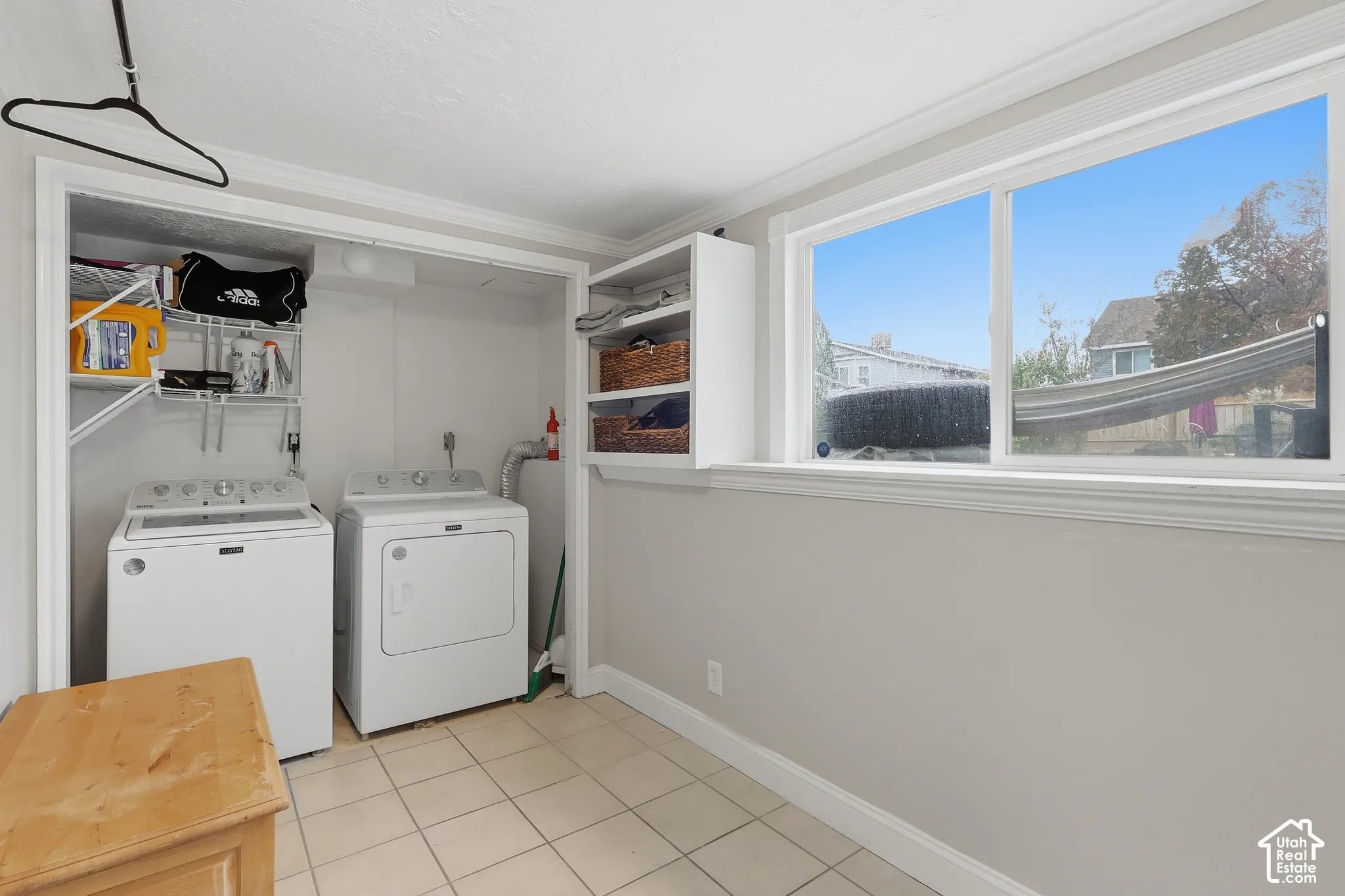 Laundry area featuring a large window, tiled flooring, built-in shelving, and a dedicated appliance space