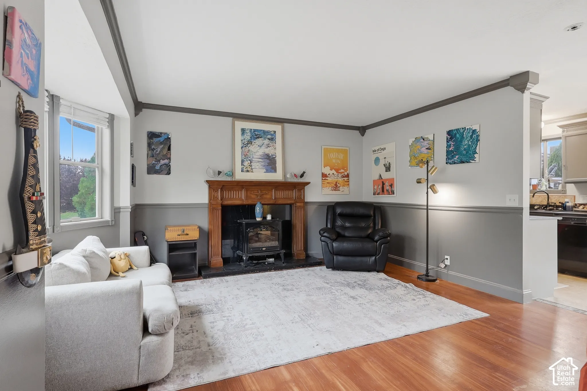 Hardwood flooring throughout, wood-paneled fireplace surround, two-tone wall treatment, built-in fireplace insert, and crown molding details