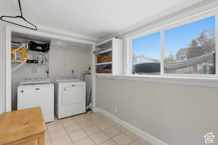 Laundry area featuring a large window, tiled flooring, built-in shelving, and a dedicated appliance space