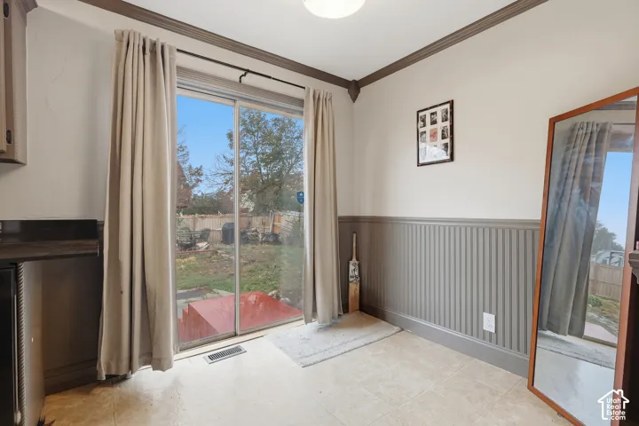 Sliding glass door, beadboard wainscoting, decorative crown molding, tiled flooring, built-in cabinetry