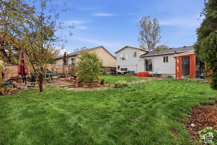 Expansive backyard with a manicured lawn, established trees, and a wooden privacy fence