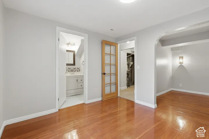 High-gloss wood-finish flooring, light grey painted walls, arched doorway, and a French door with glass panels