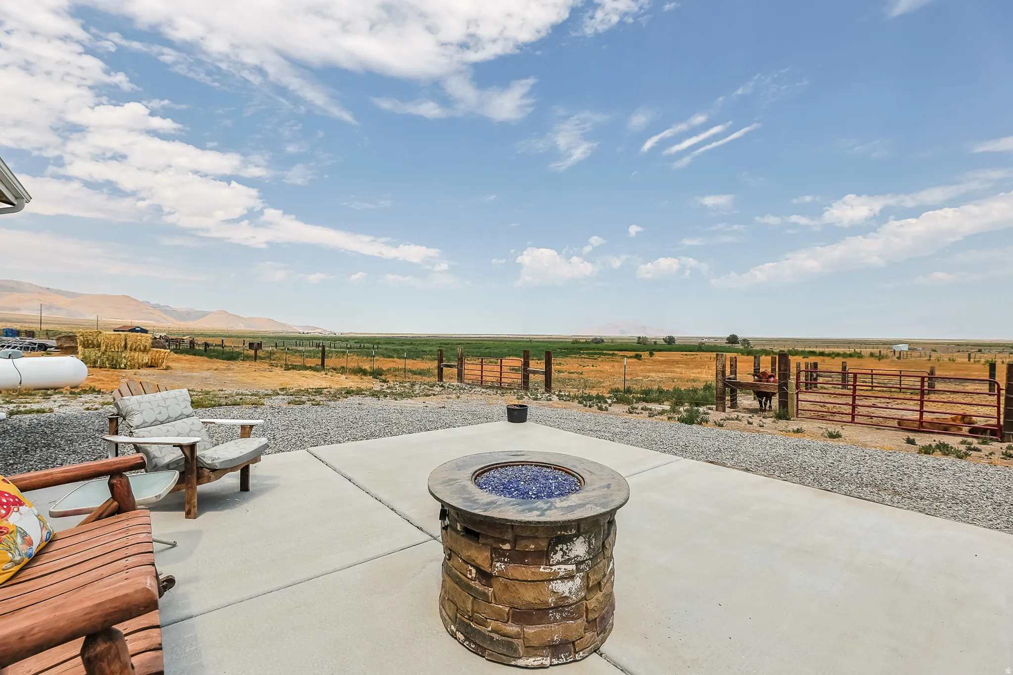 Concrete patio featuring a stacked stone fire pit with blue fire glass