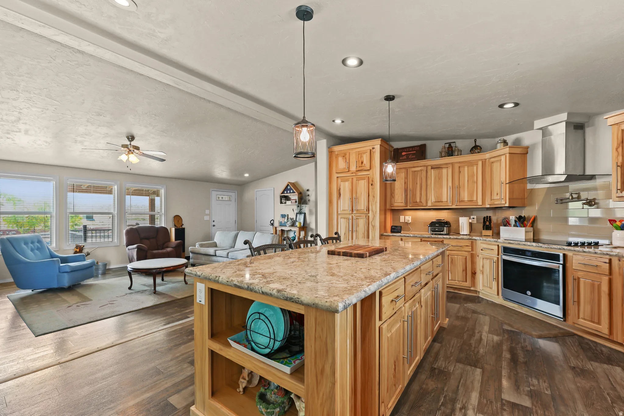 Open-concept living space featuring wood-finish flooring, recessed lighting, and a ceiling fan
