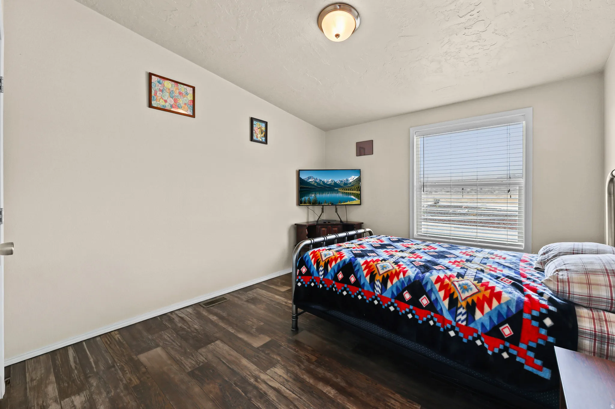 Wood-finish flooring, neutral wall paint, and a window with horizontal blinds
