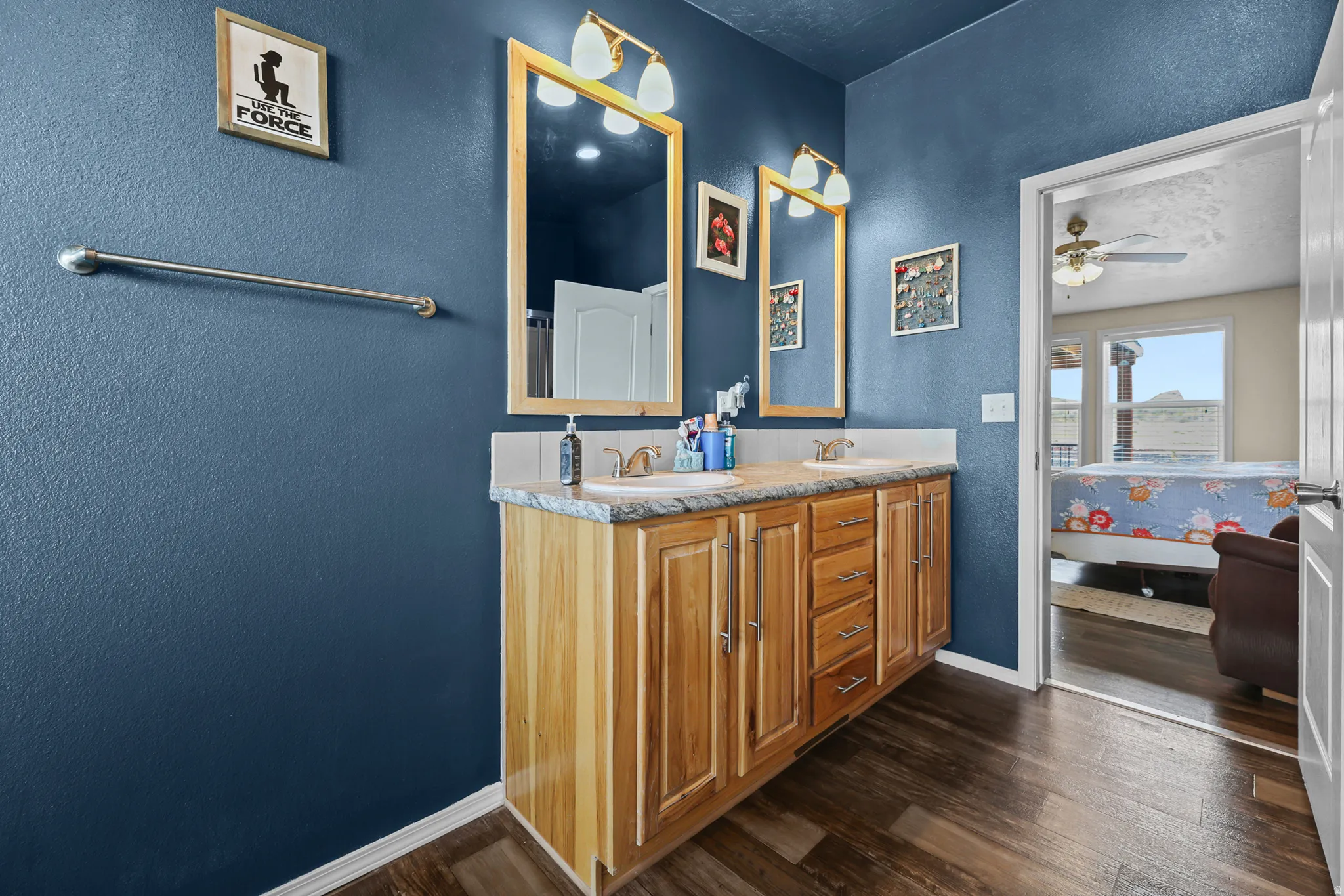 Dual vanity with light wood cabinetry, stone-finish countertop, and undermount sinks