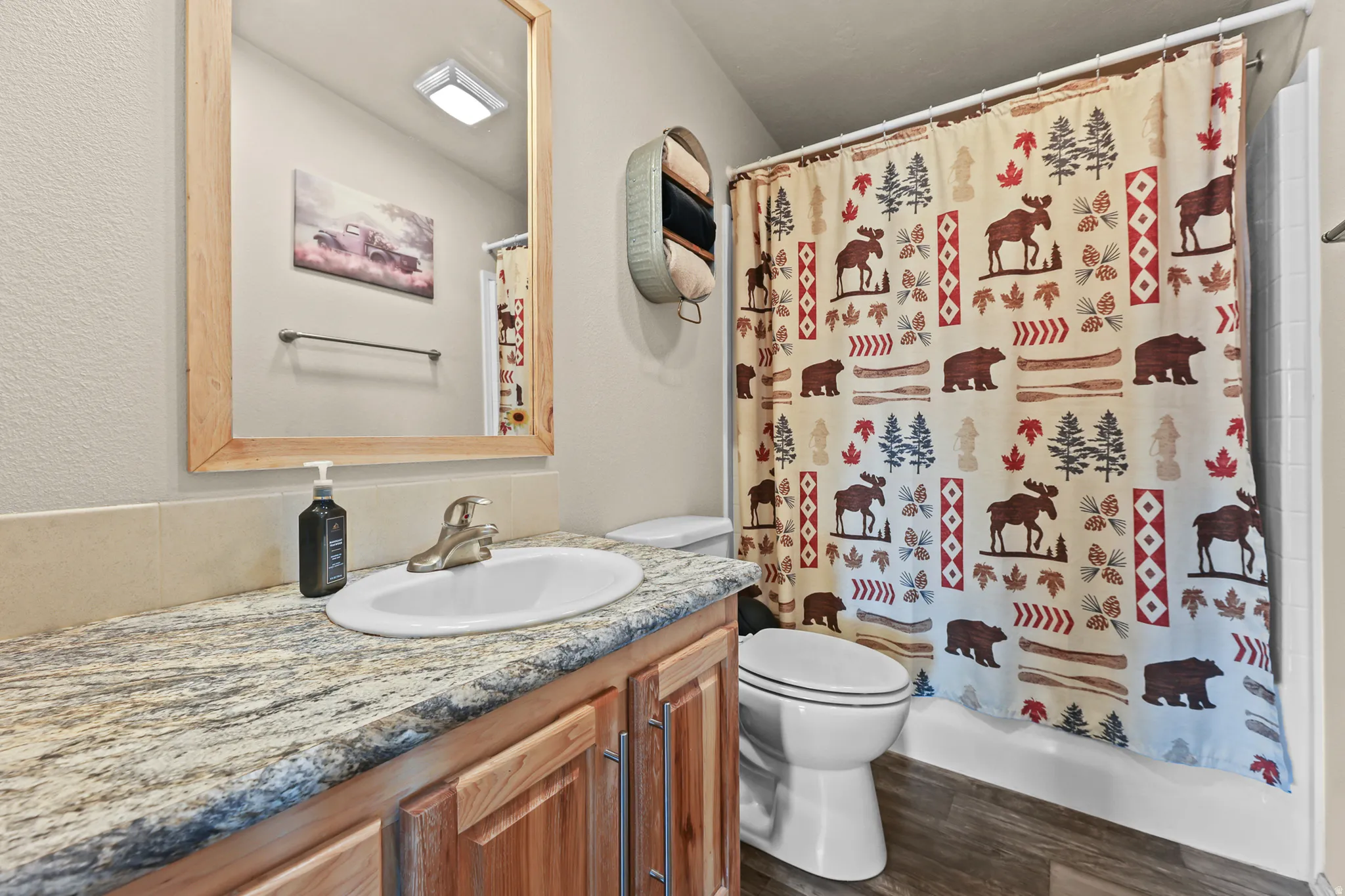 Bathroom featuring a single vanity with an integrated sink, patterned countertop, and wood-finish cabinetry