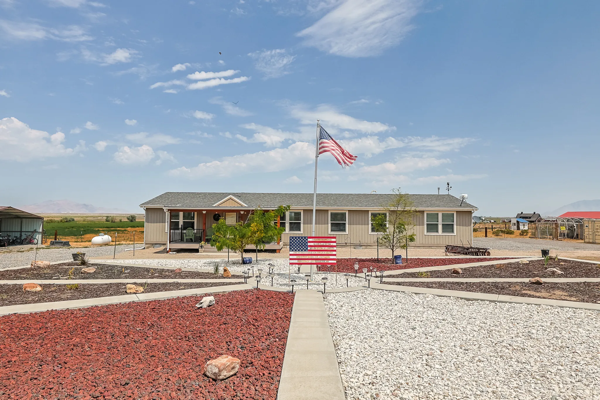 Single-story residence with a covered front porch and a gravel-covered yard featuring decorative rock beds