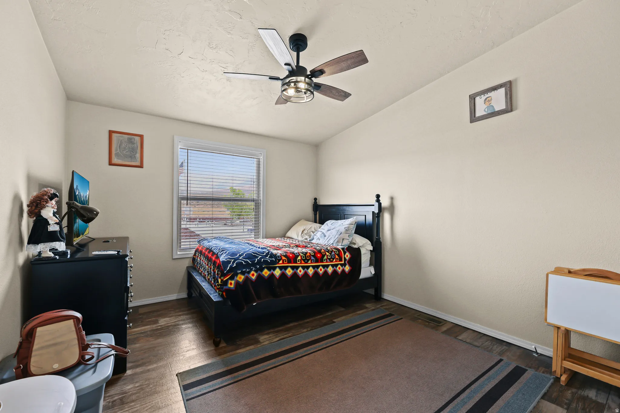 Wood-finish flooring, ceiling fan with integrated lighting, window with horizontal blinds, and a neutral color palette