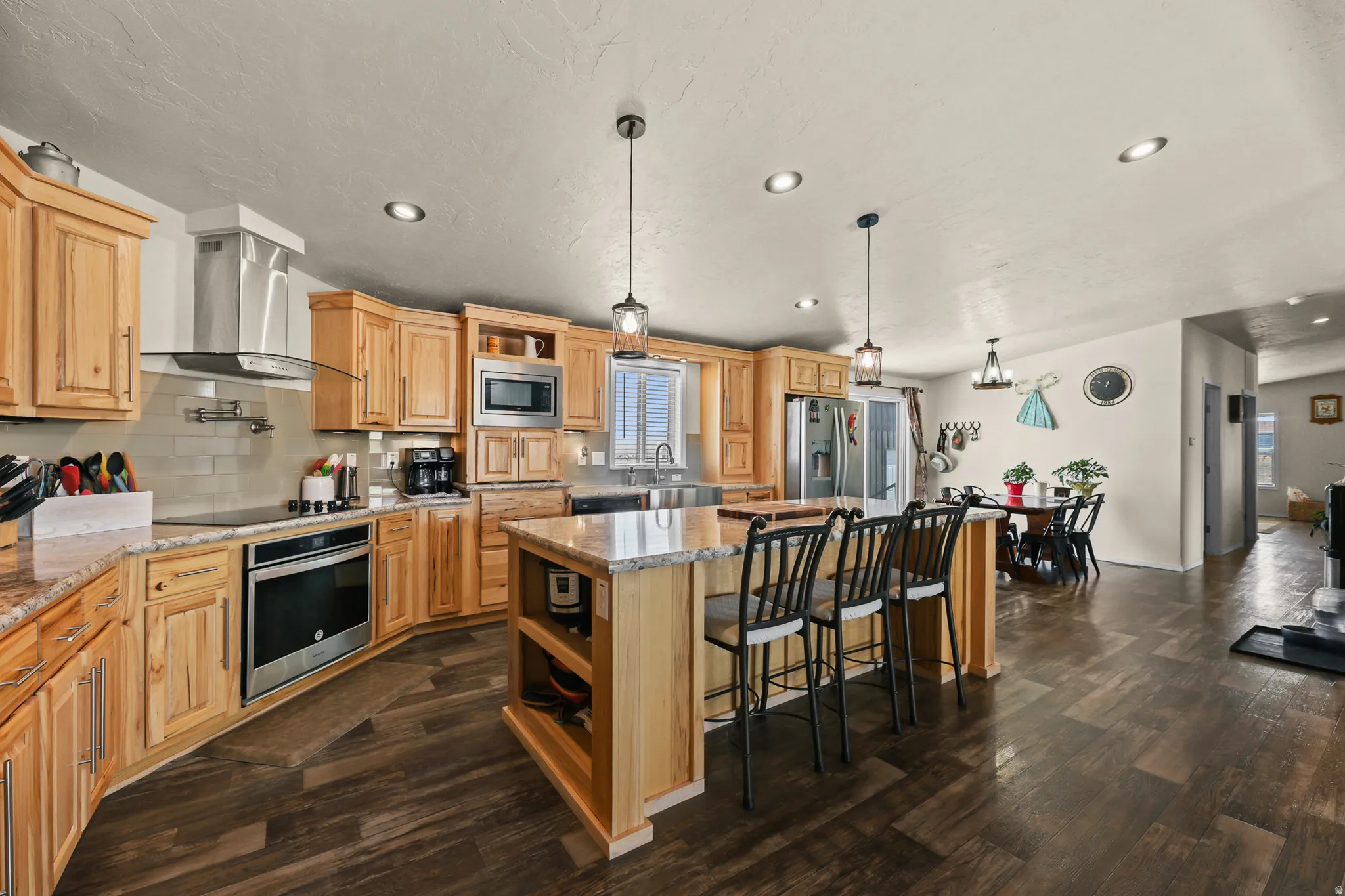 Light wood-finish cabinetry with stainless steel appliances, granite-style countertops, and a subway tile backsplash