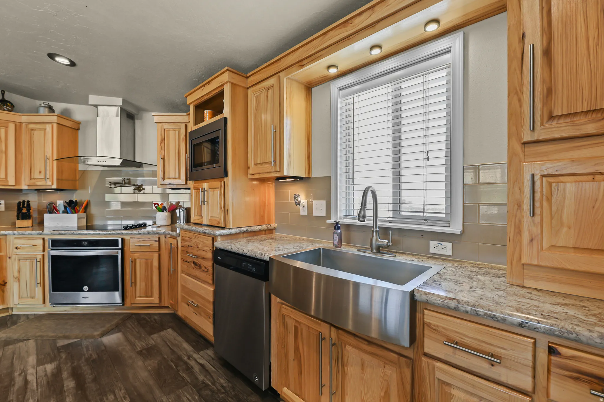 Wood-finish flooring, stainless steel appliances, light wood cabinetry, quartz countertops, and a farmhouse-style sink
