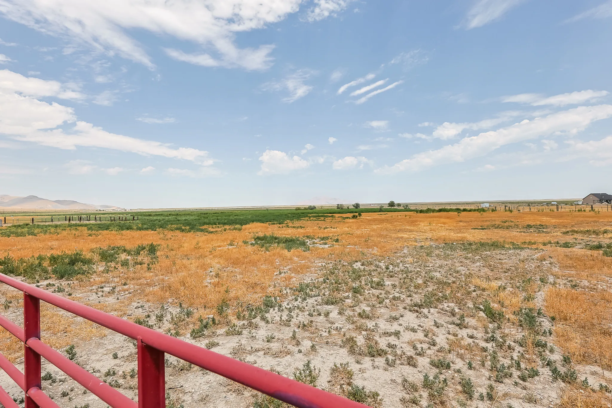 Expansive rural landscape featuring a red metal fence