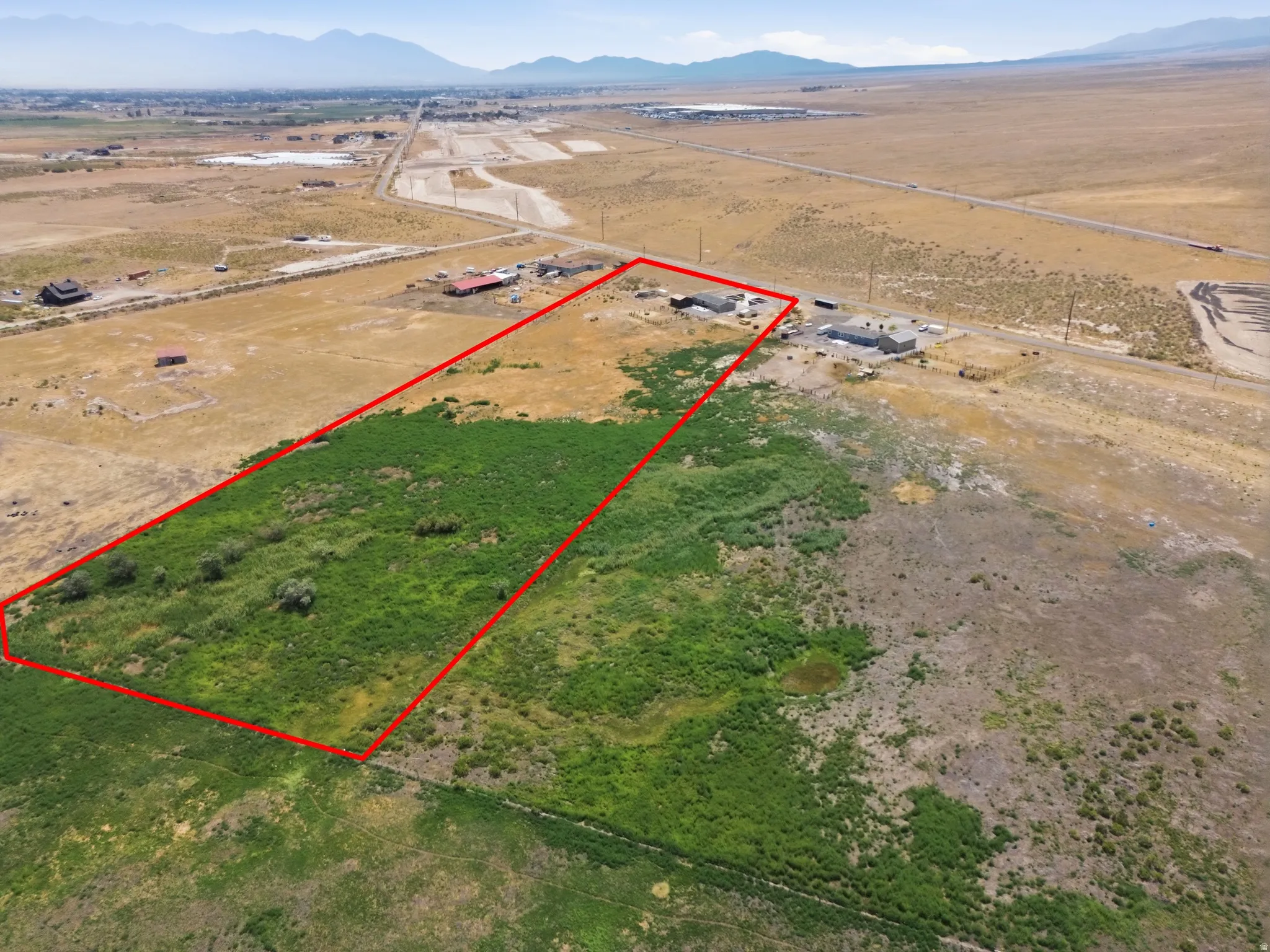 Expansive lot featuring varied terrain, a small pond, and distant mountain scenery