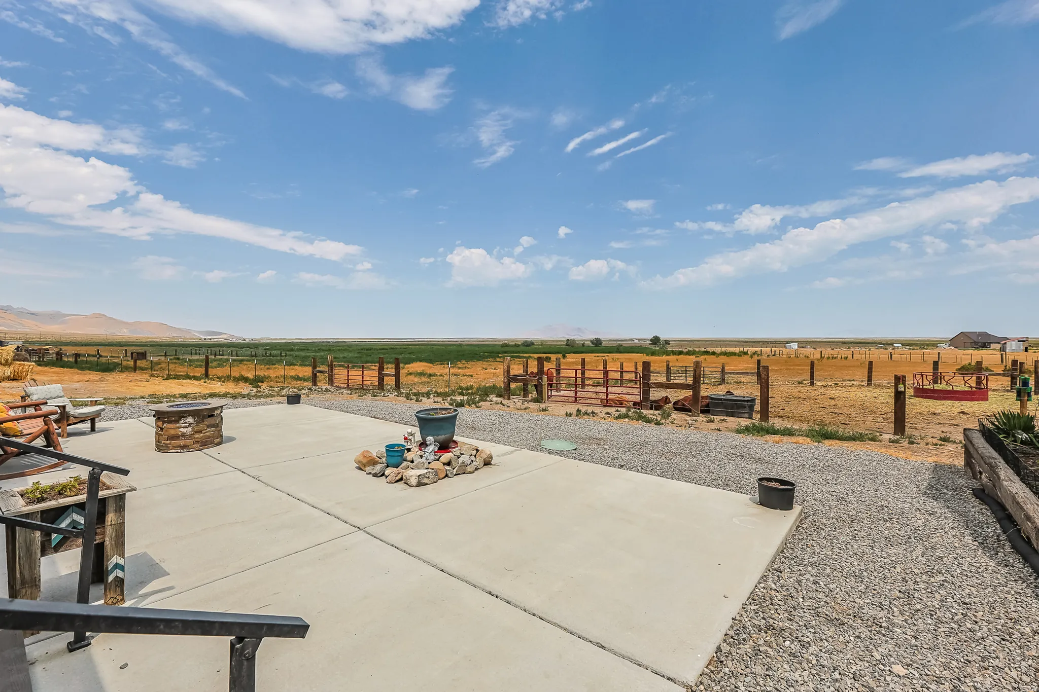 Expansive concrete patio with a built-in fire pit, surrounded by gravel landscaping