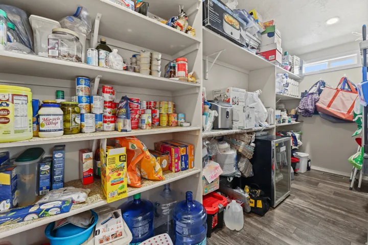 Expansive pantry featuring extensive built-in shelving, wood-finish flooring, and a transom window providing natural light