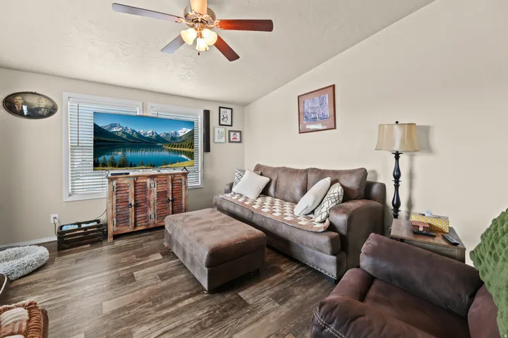 Wood-finish flooring, ceiling fan, and window with blinds