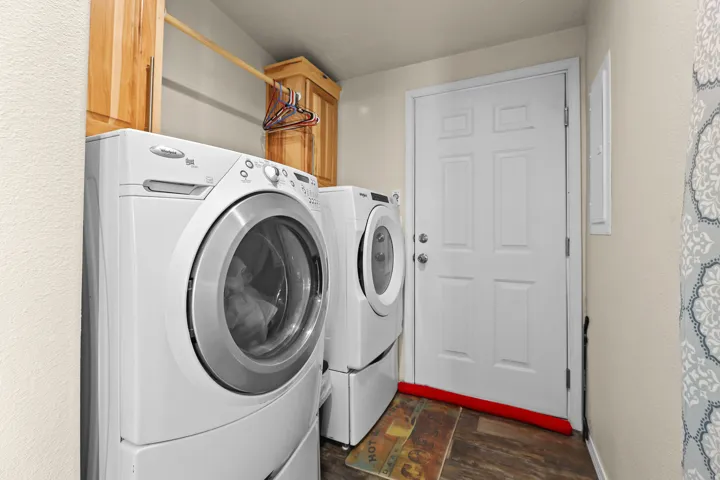 Dedicated laundry area with wood-finish flooring, light-toned walls, and wood cabinetry
