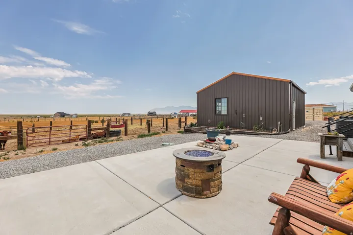 Concrete patio with a stone-finish fire pit, gravel landscaping, and a large metal-sided outbuilding