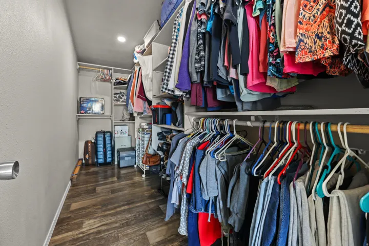 Walk-in closet featuring wood-finish flooring, recessed lighting, and integrated shelving with hanging rods