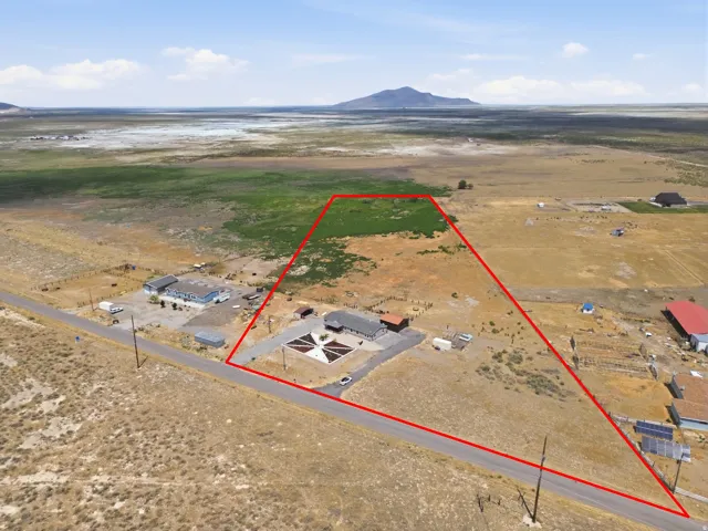 Expansive property featuring a paved road, multiple structures, and a large open field