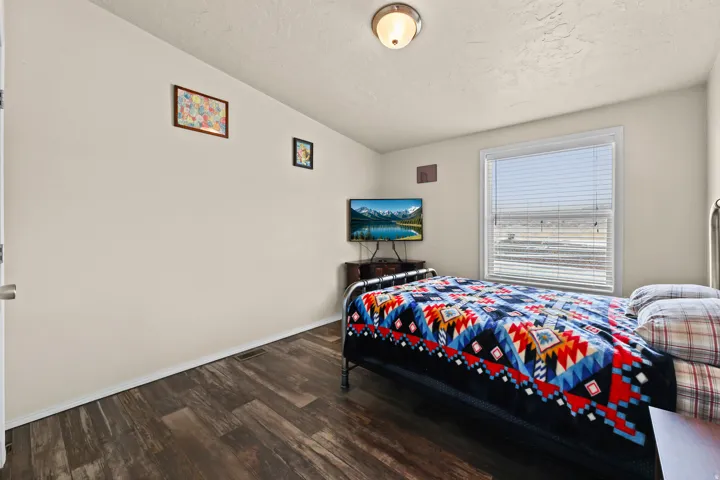 Wood-finish flooring, neutral wall paint, and a window with horizontal blinds