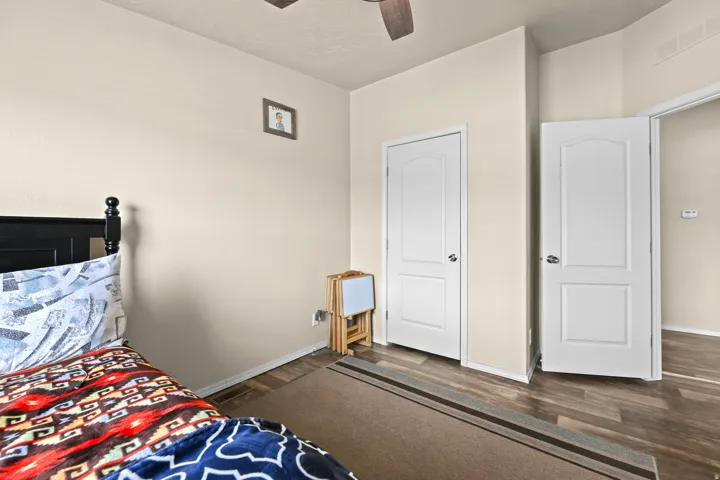 Wood-finish flooring, white paneled doors, and a ceiling fan