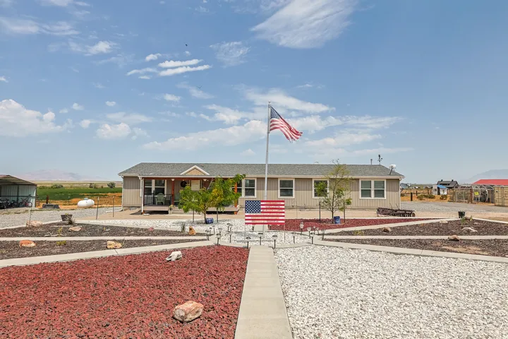 Single-story residence with a covered front porch and a gravel-covered yard featuring decorative rock beds