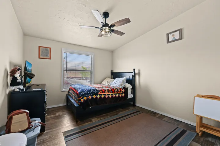 Wood-finish flooring, ceiling fan with integrated lighting, window with horizontal blinds, and a neutral color palette