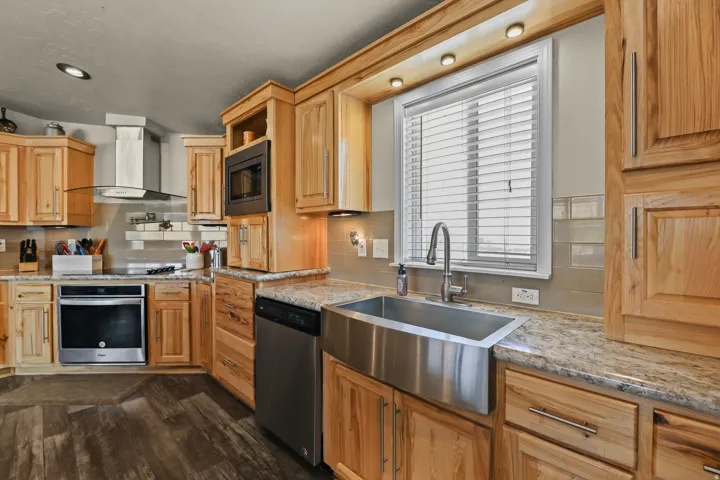 Wood-finish flooring, stainless steel appliances, light wood cabinetry, quartz countertops, and a farmhouse-style sink