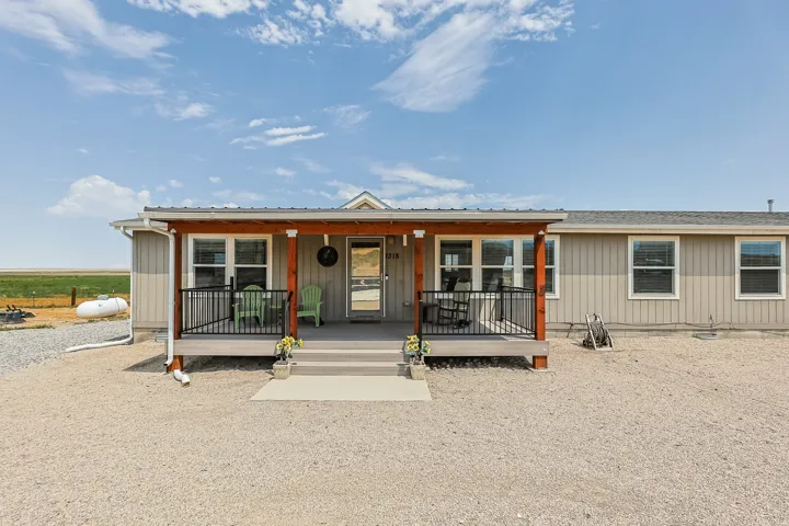 Front porch with a metal roof, wood columns, and black railings