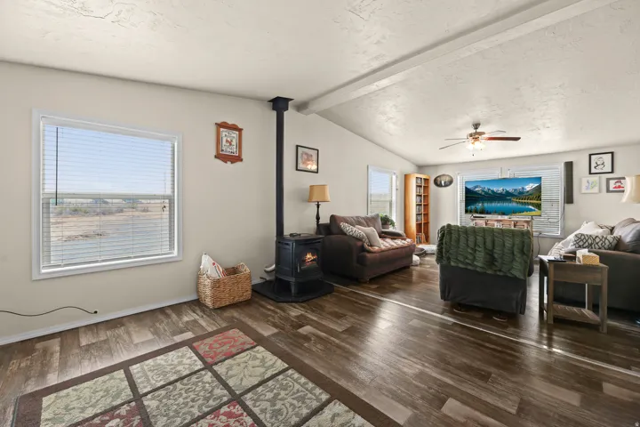 Spacious living area featuring wood-finish flooring, a wood-burning stove, and multiple windows