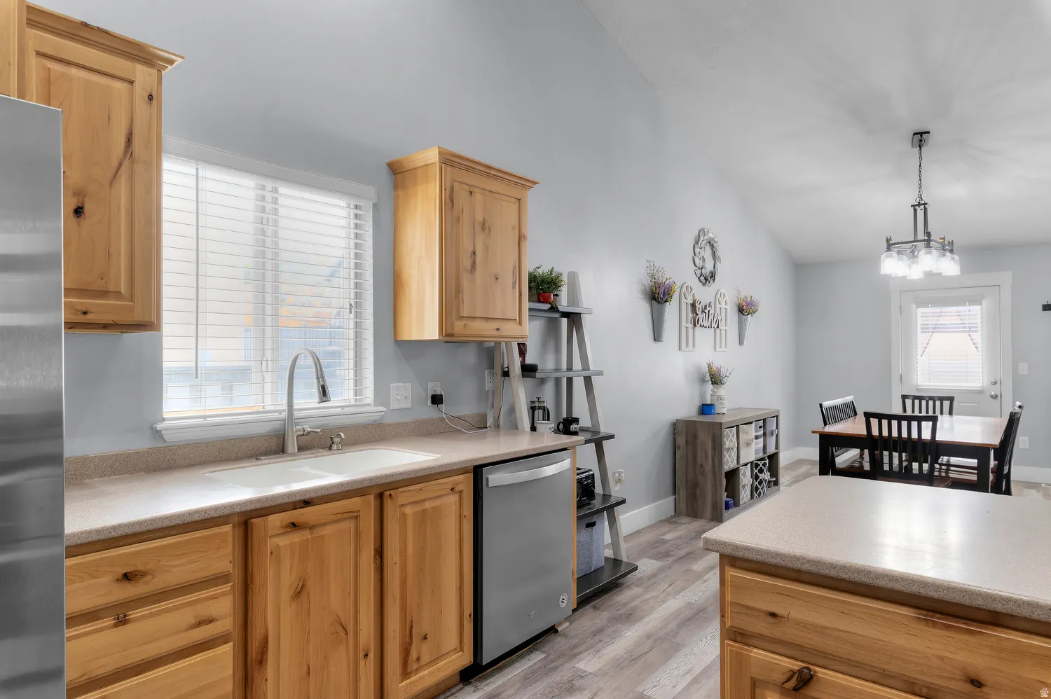 Kitchen featuring wood cabinetry, stainless steel dishwasher, and a double basin sink