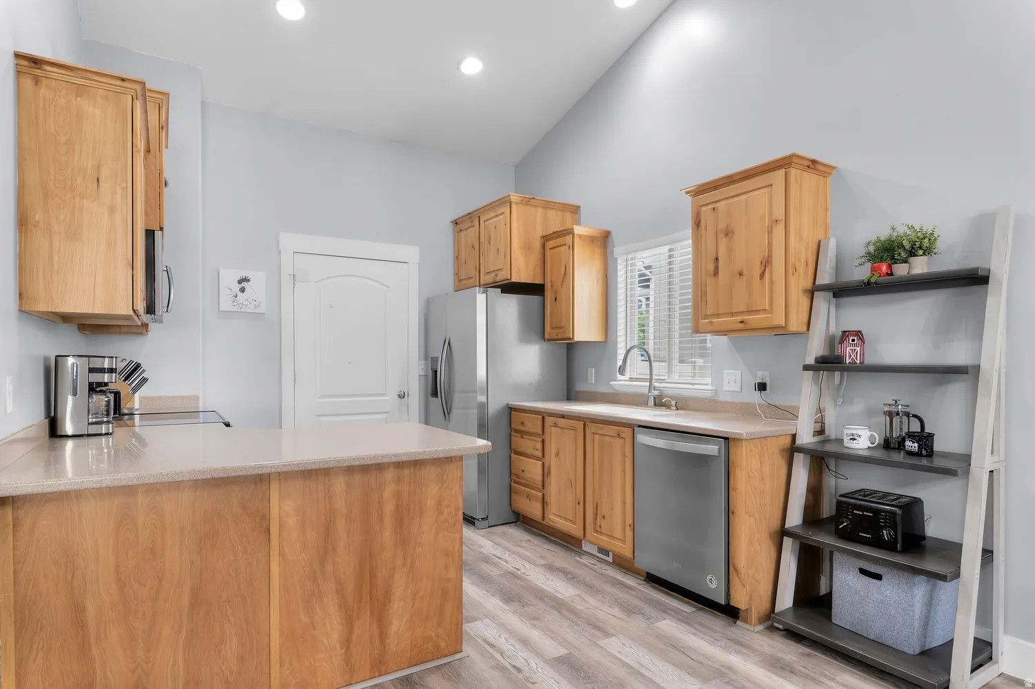 Kitchen featuring wood cabinetry, stainless steel appliances, light-toned countertops, and wood-finish flooring